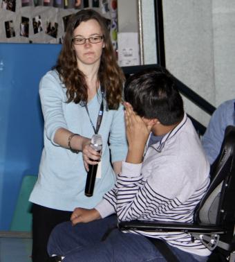 teacher holding microphone for young man in wheelchair